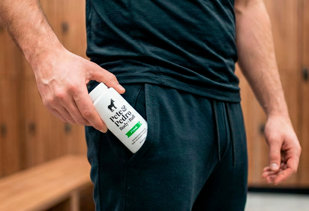 Man holding Pete & Pedro body-and-ball powder near waistband in gym shorts.